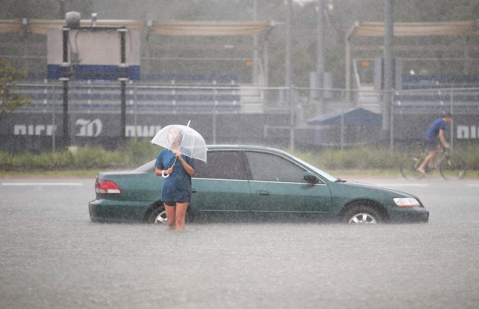 Mari Zertuche walks through a flooded parking lot on the campus of Rice University 