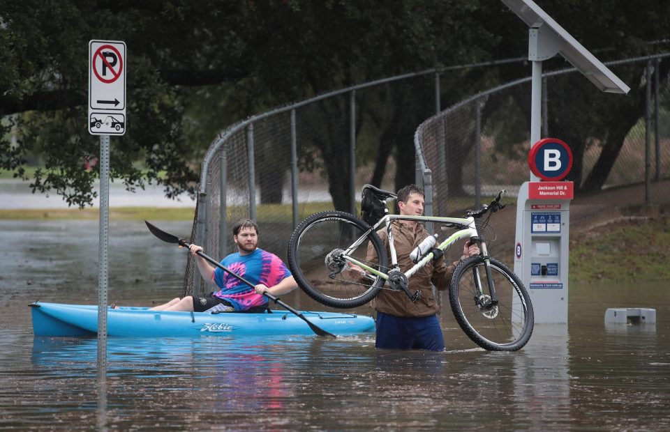 A man uses a kayak to navigate a flooded street