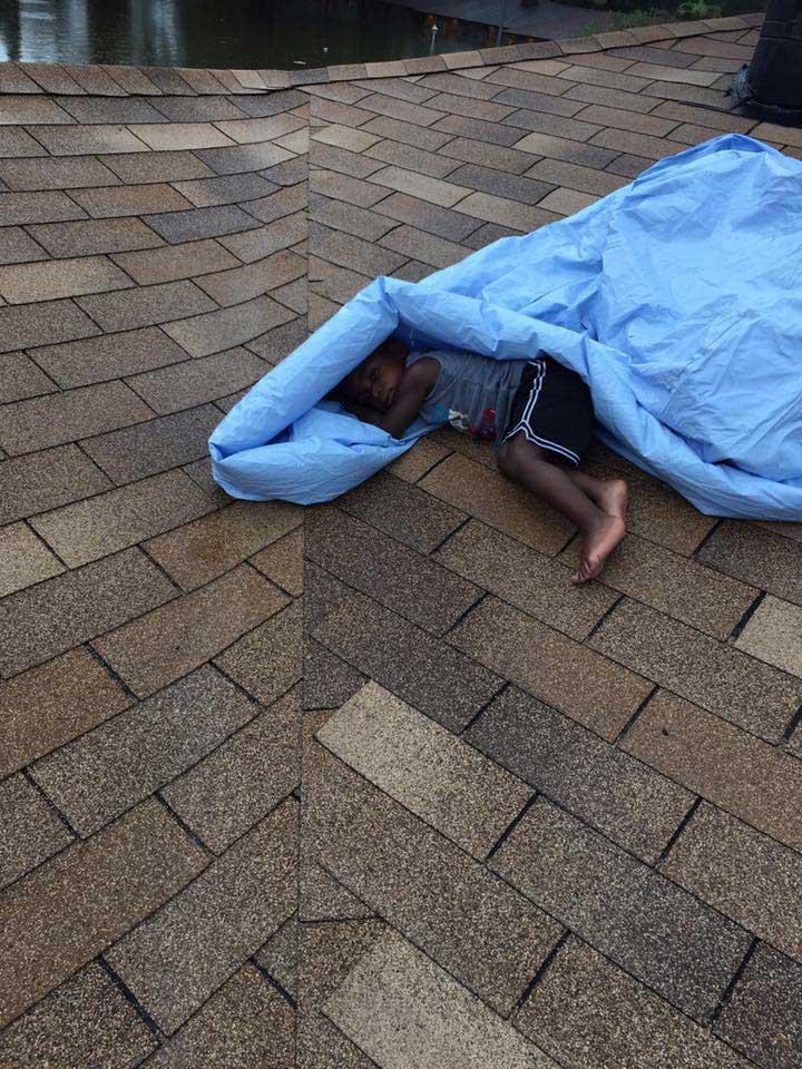 A little boy lies under tarpaulin as Hurricane Harvey leaves many families stranded