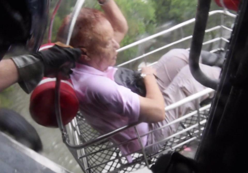 A US Coast Guard helicopter crew rescue one of five people from floodwaters in a southeastern Houston neighbourhood