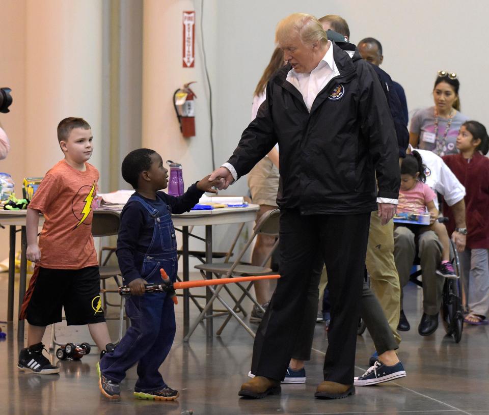 Trump holds the hand of a young boy whose family were impacted by the hurricane