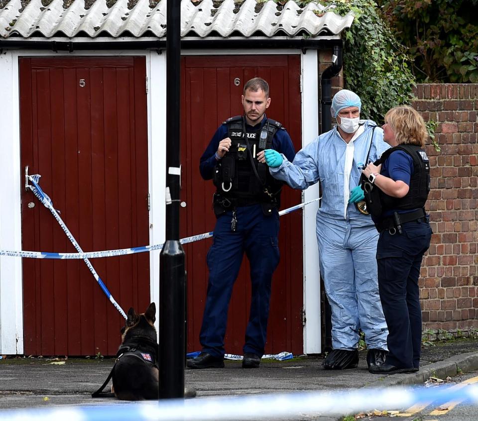 A forensic officer talks to officers near the crime scene in Forest Gate