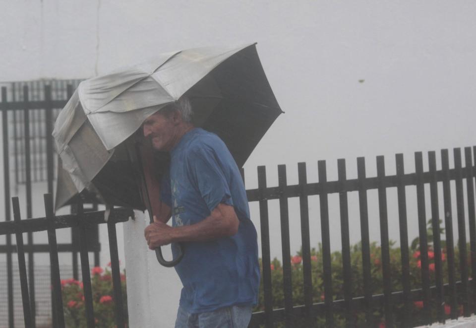  A man carrying an umbrella walks on a street in Puerto Rico