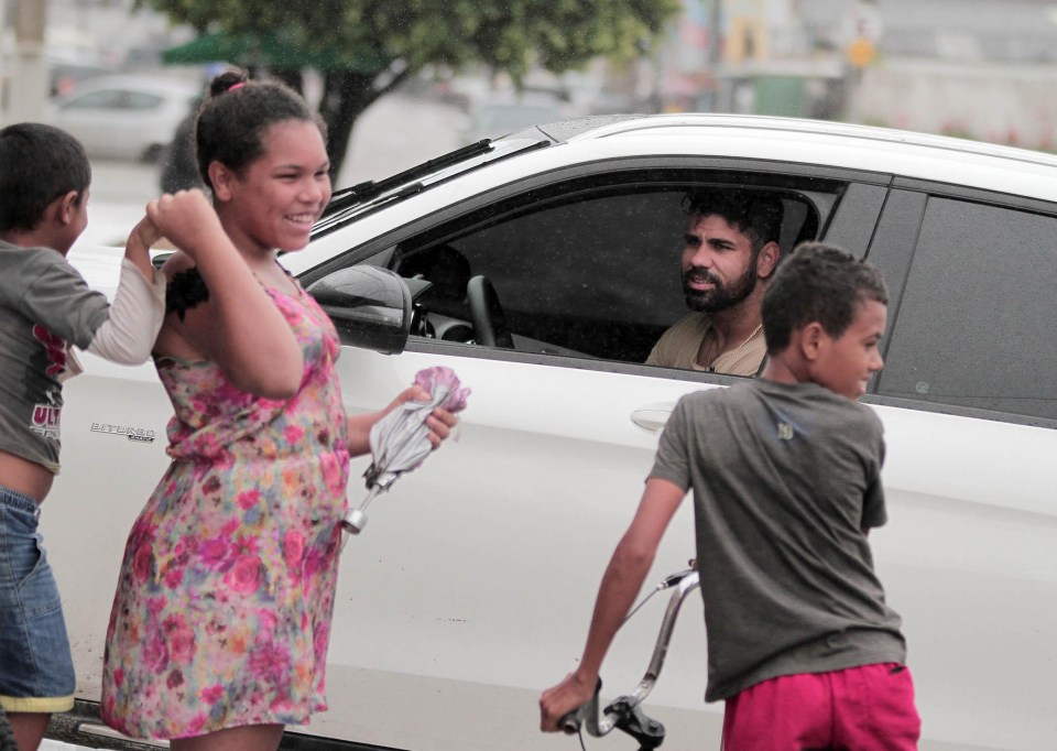 Costa was seen chatting to kids on the street as it poured with rain around him