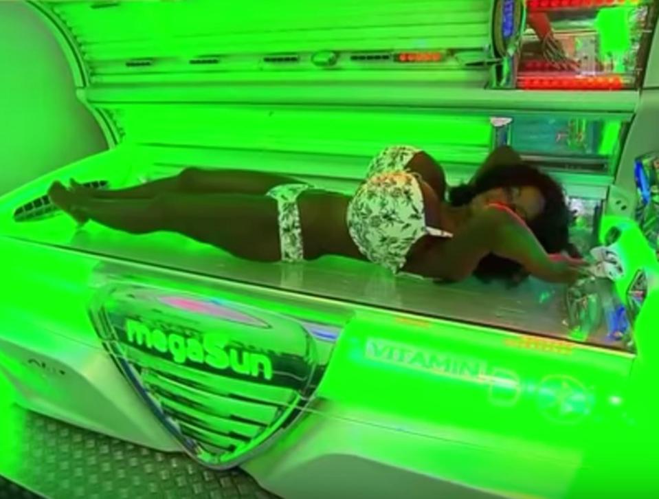  Martina poses on a tanning bed as she enhances her deep mahogany skin