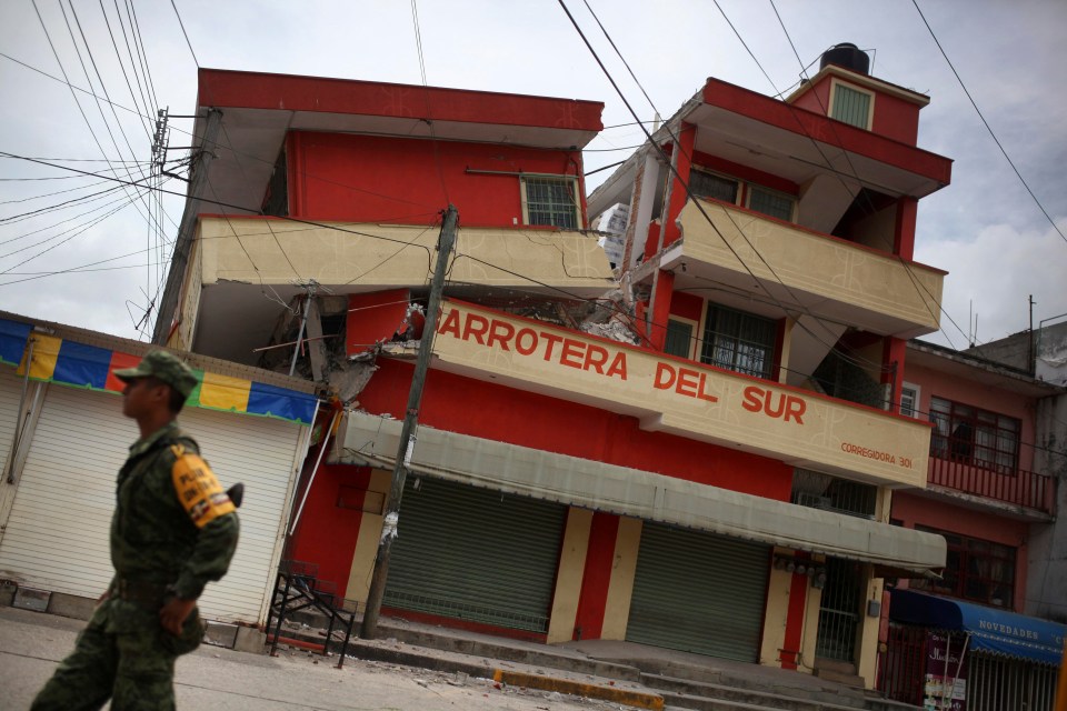 A soldier walks by a partially collapsed building in Matias Romero, one of the worst-hit towns in the region