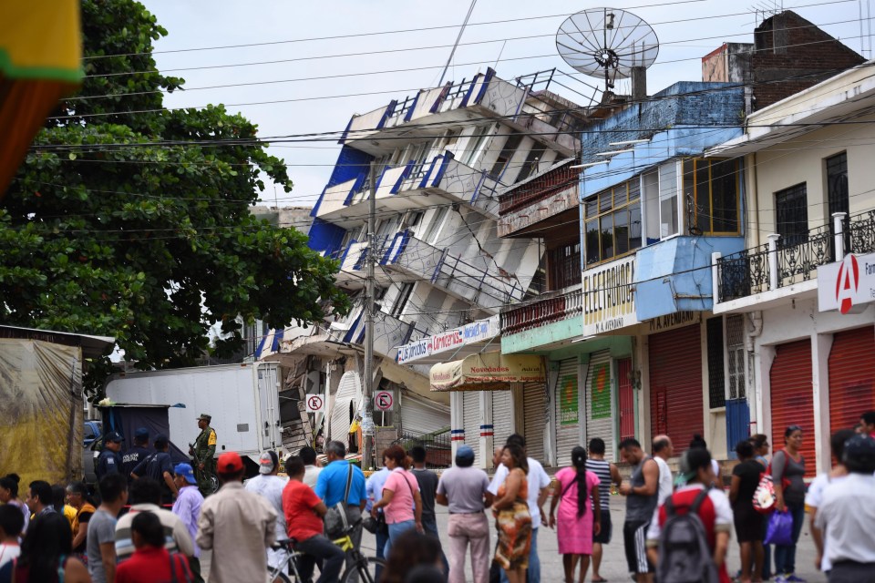 Residents look at the damaged hotel following the 8.2 magnitude quake