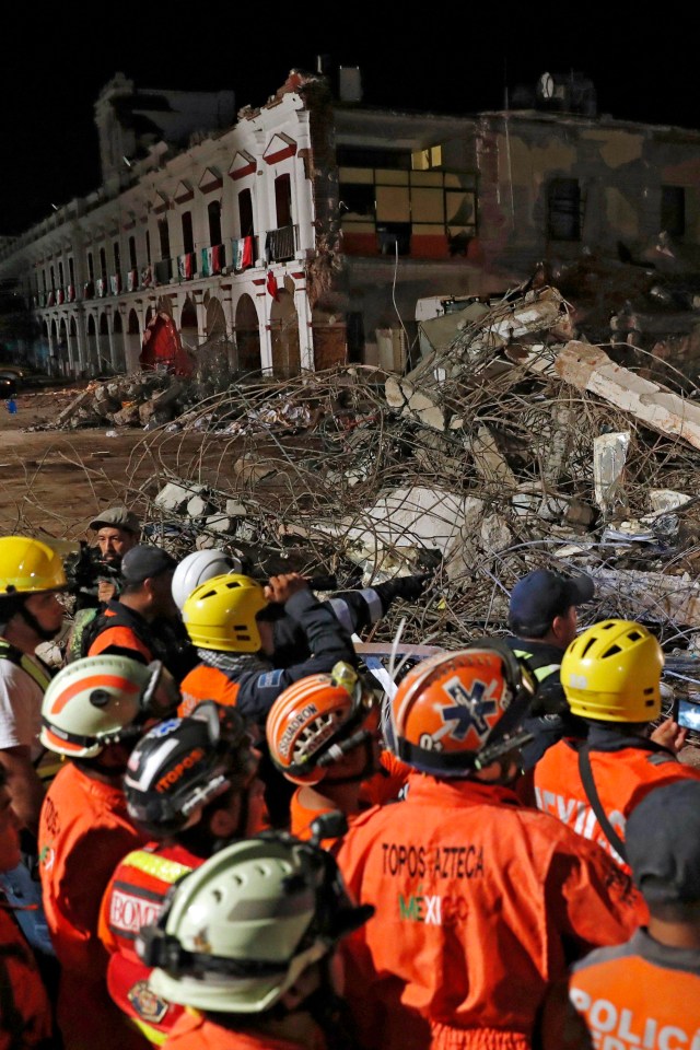 Emergency Services workers inspect the debris of a collapsed building in Juchitan town