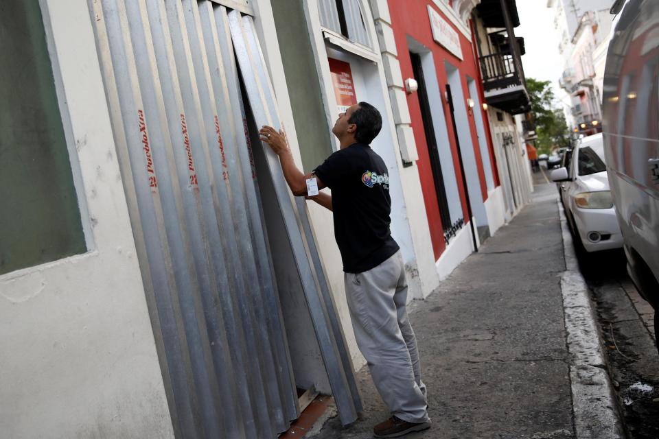  A man covers the windows of a supermarket in San Juan as the superstorm approaches