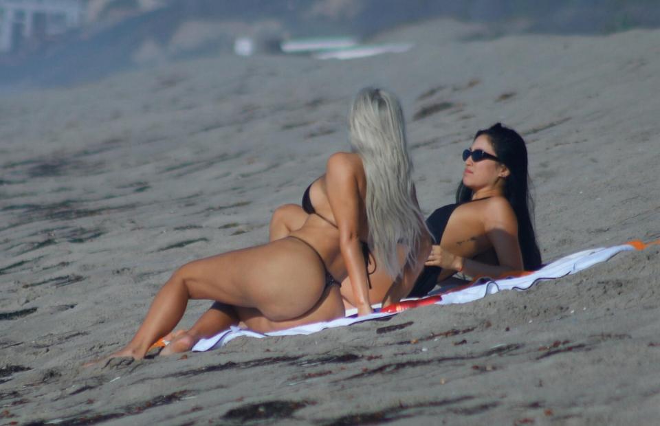  Kim soaked up the sun behind her pal as they reclined on a towel