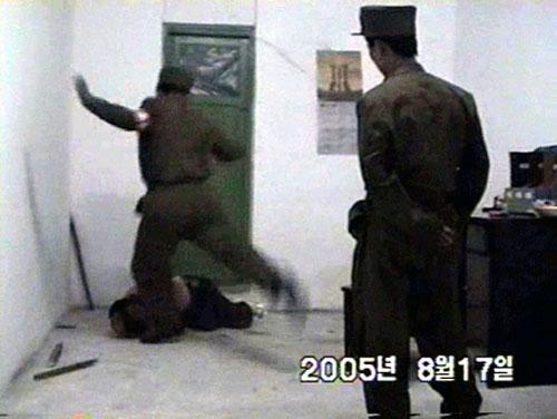  One of the guards is pictured kicking the man while he cowers on the ground