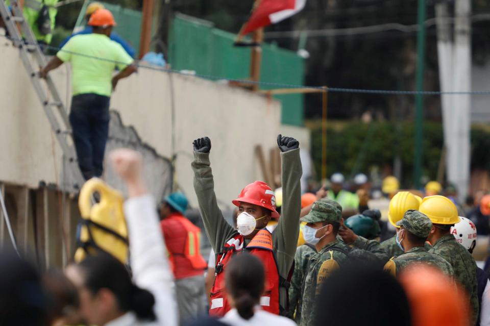  A rescue worker raises his hands to ask for silence during the search for students after an earthquake at Enrique Rebsamen school in Mexico City