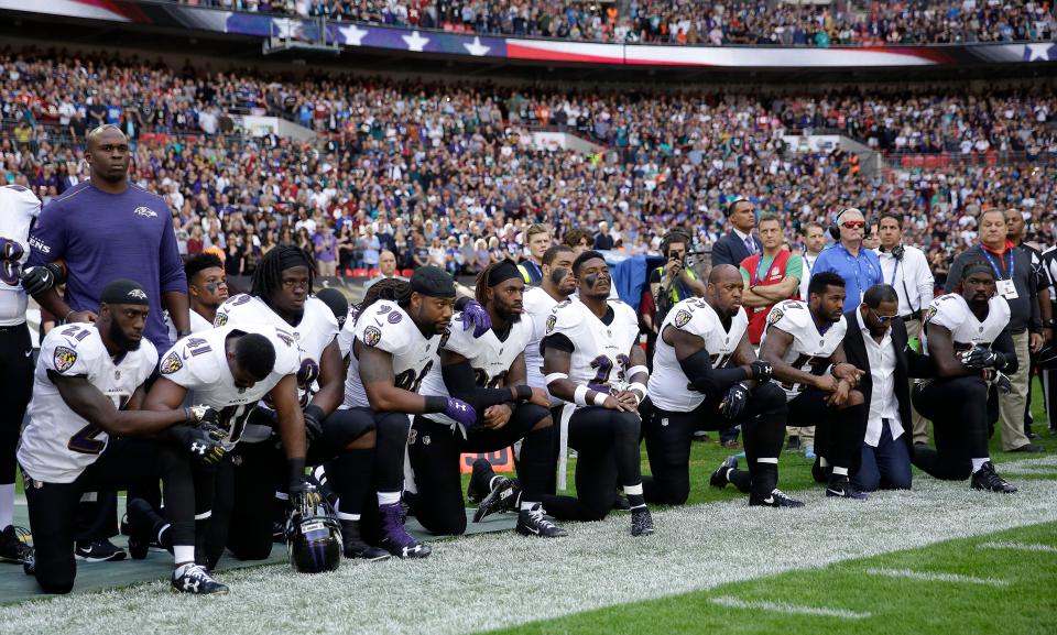 Baltimore Ravens players, including former player Ray Lewis, second from right, kneel down during the playing of the U.S. national anthem