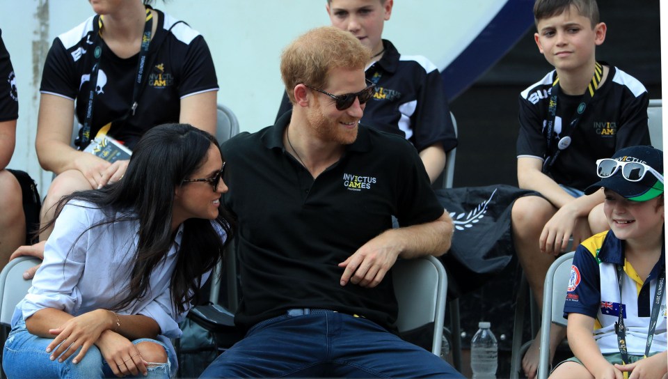 Prince Harry put his arm around Meghan's chair as the couple joked with a child watching the match