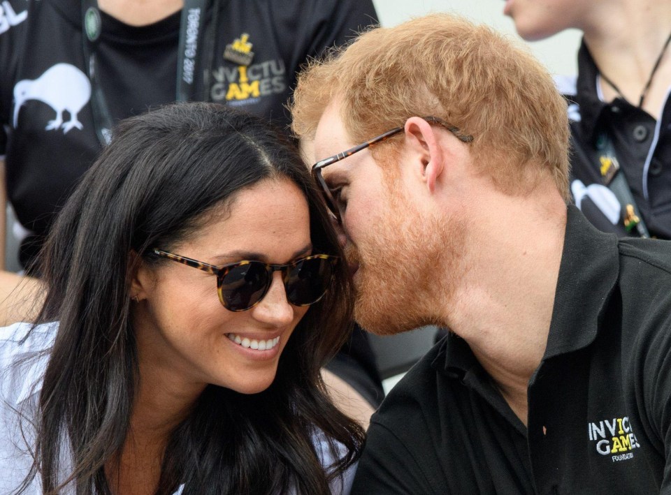 Meghan smiles as she chats to Prince Harry, who spoke intimately in her ear