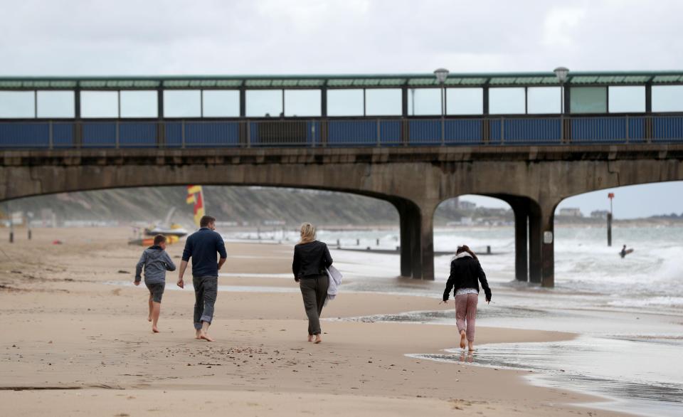  People walk along Boscombe beach, Bournemouth, as Britain is on course for heavy rain and gales