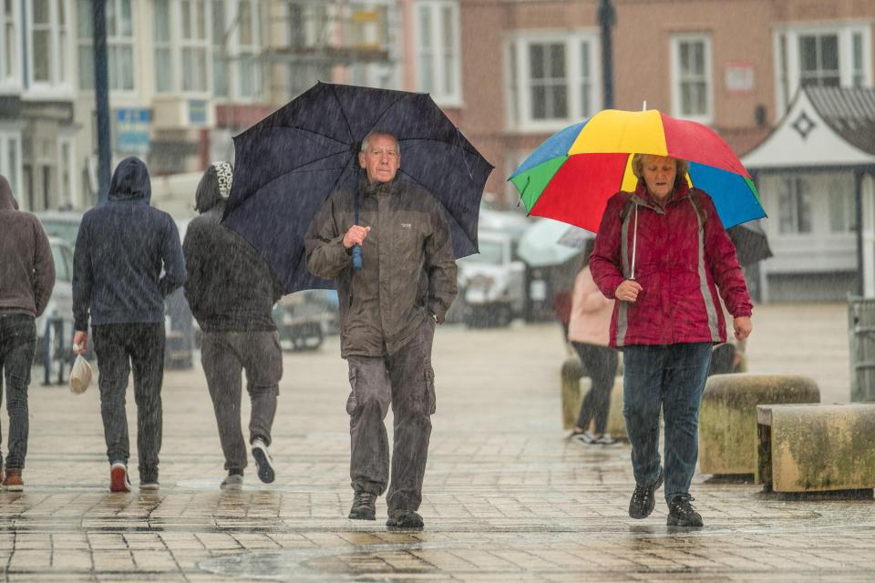  Torrential rain pours down on pedestrians sheltering under their umbrellas at the seaside in Aberystwyth in Wales