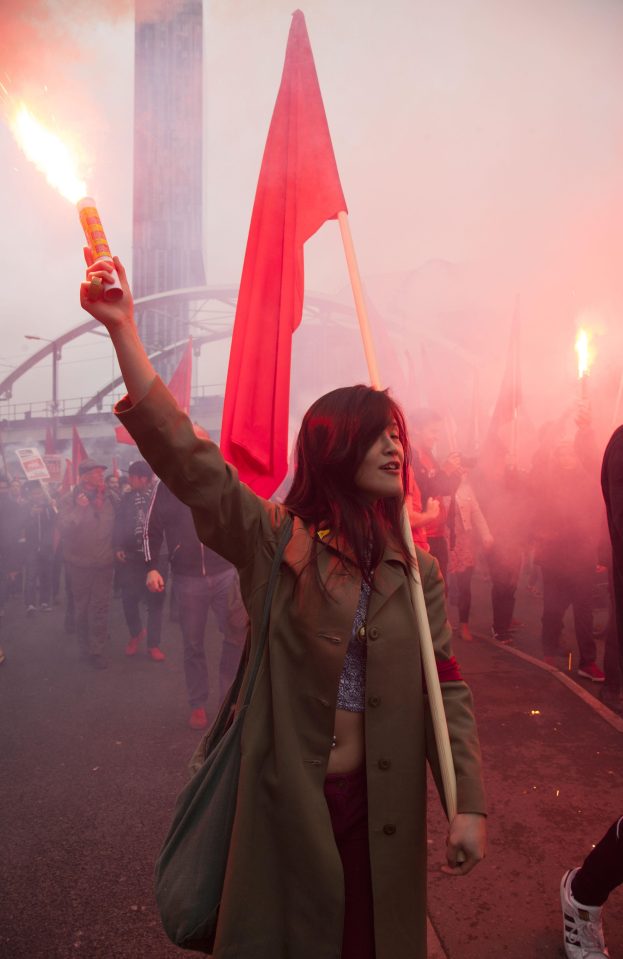  A socialist protester waves a red flag and a flare during the march