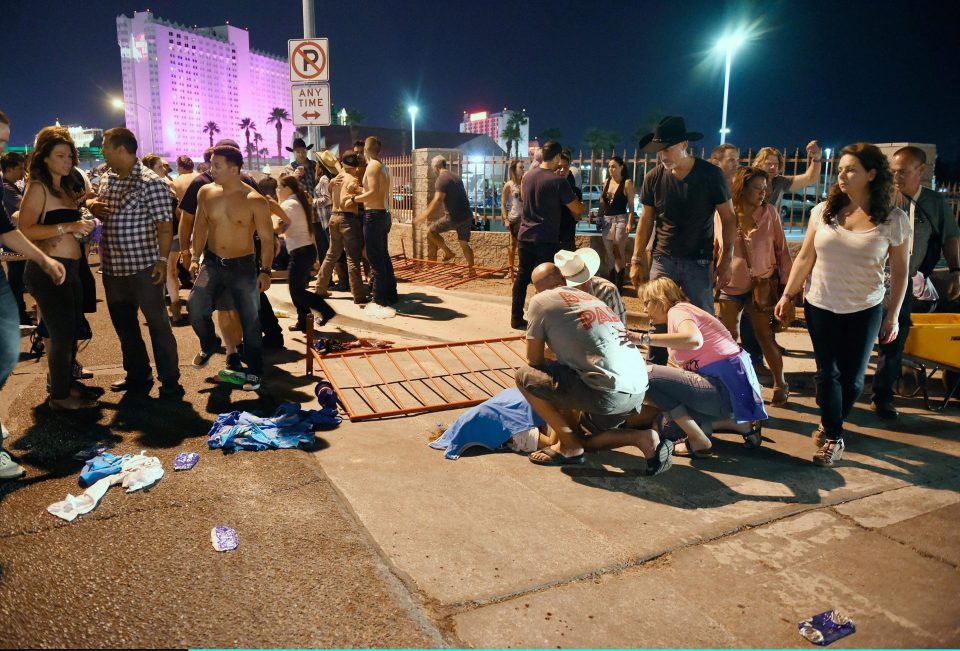  Onlookers tend to the wounded outside the festival ground after the shooting