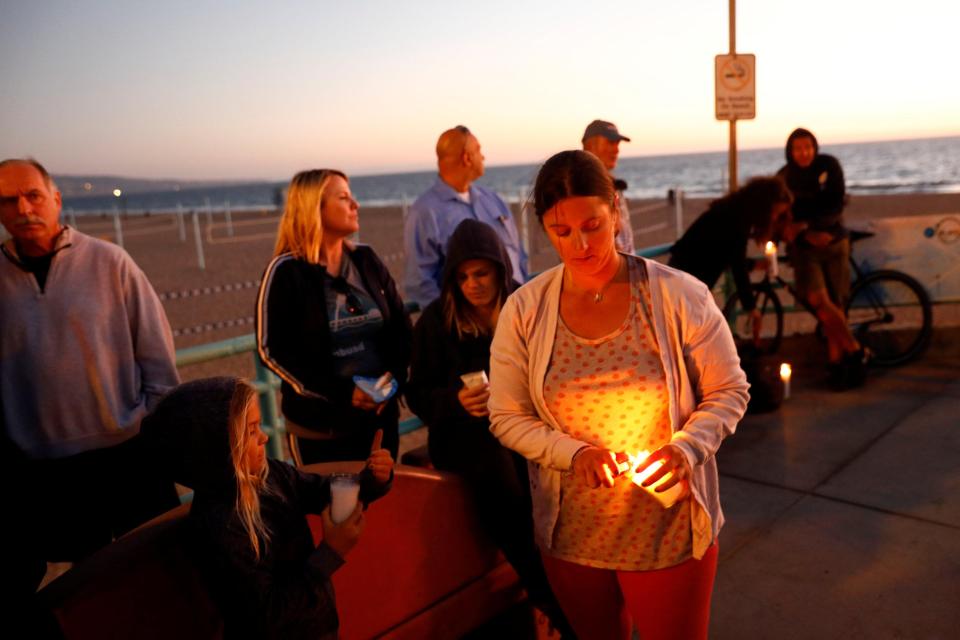  People light candles during a memorial for victims of the shooting