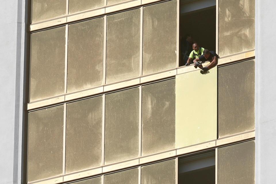 Workers board up a broken window at the Mandalay Bay hotel, where shooter Stephen Paddock conducted his mass shooting 