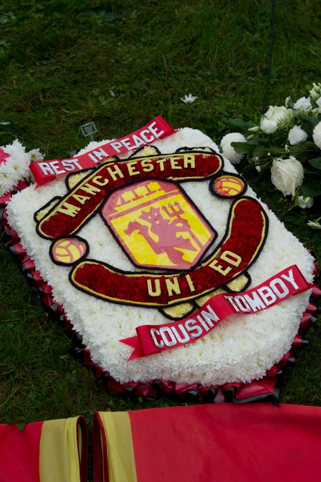 A Man Utd crest pictured amongst the colourful and elaborate funeral wreaths