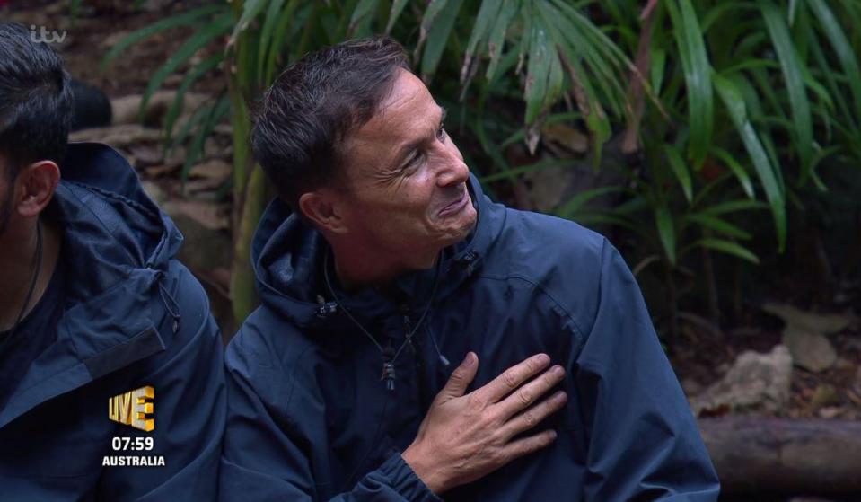  Dennis taps his heart with his fingers as he finds out his fate for the Bushtucker Trial