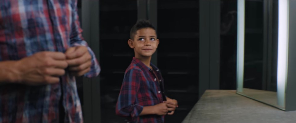 The youngster stares up at his father while wearing a new shirt from the collection