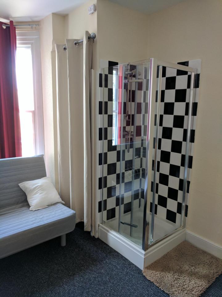  The shower stands in the corner of the room just a few feet from the kitchen area