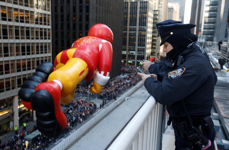  Armed officers took a break from keeping New York safe to text and watch a balloon shaped like Ronald McDonald