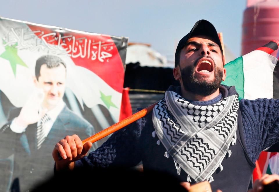  A protestor waves the Palestinian flag at the Jaramana camp in Damascus