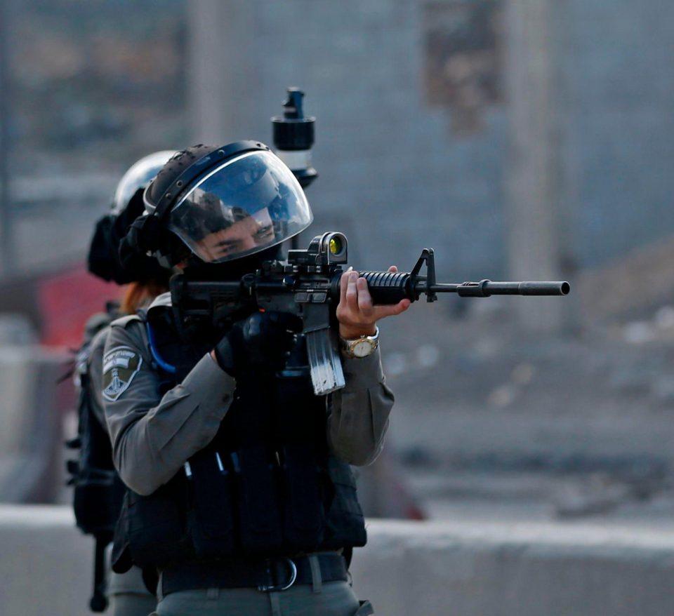 An Israeli border guard takes aim as Palestinian protesters gather in the West Bank city of Ramallah