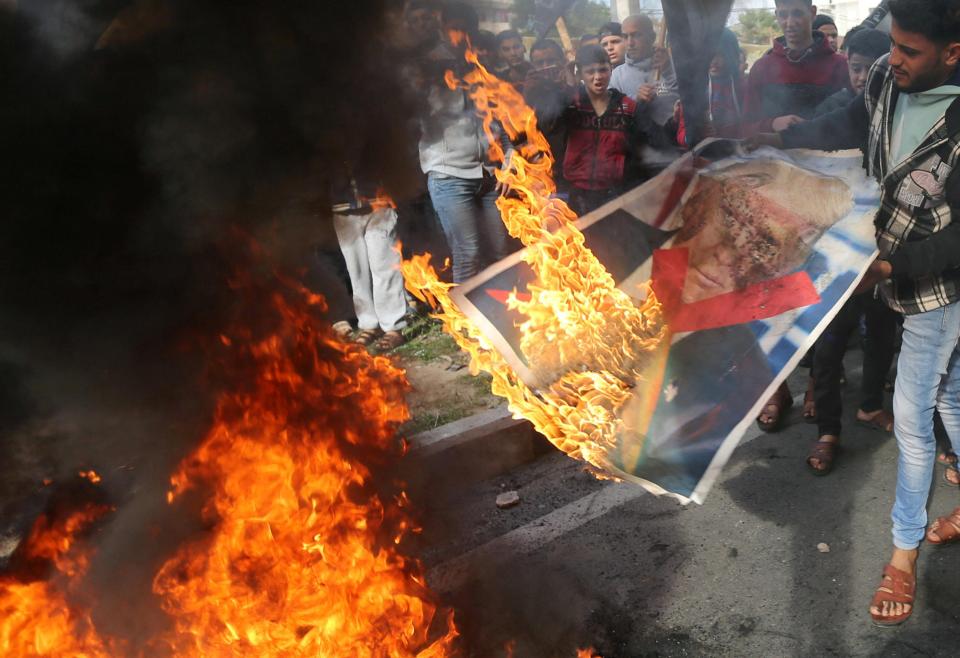 Palestinian demonstrators burn a poster of Donald Trump during a protest near the central Gaza Strip