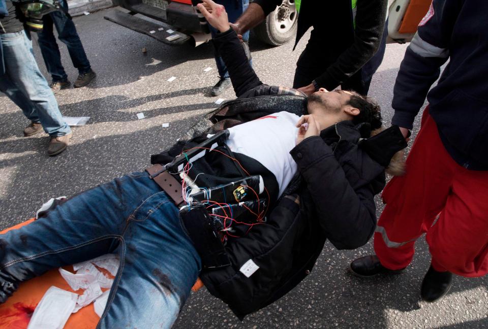 A Palestinian man, wearing a reported suicide vest, is carried to an ambulance after being shot 