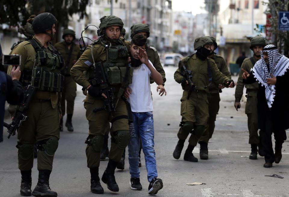 Israeli soldiers detain a Palestinian youth during clashes at a protest in the West Bank city of Hebron