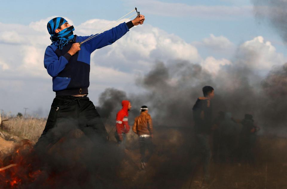 A demonstrator uses a slingshot to launch rocks towards Israeli troops