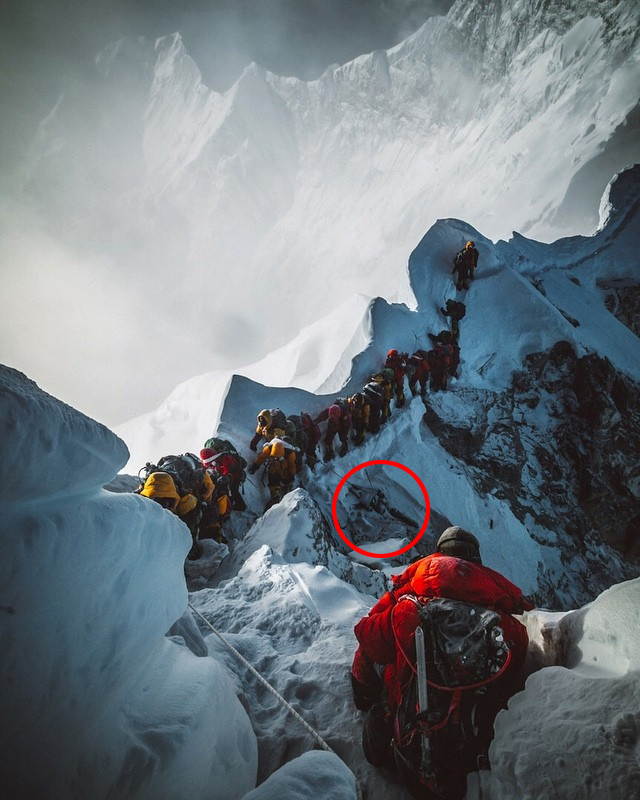  Mountaineers filing past a body near the summit, where the frozen cadavers of many fallen climbers still remain