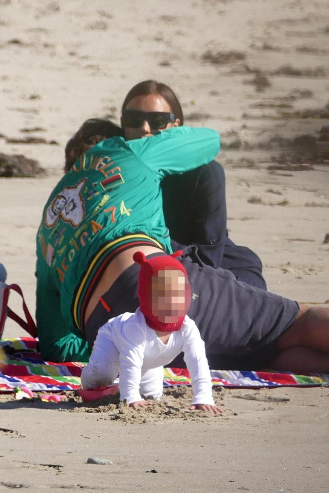  Bradley and Irina enjoyed a tender moment as they hugged while Lea crawled on the sand