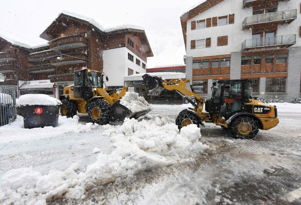  Workers remove snow beside the Zermatt train station after heavy snowfall