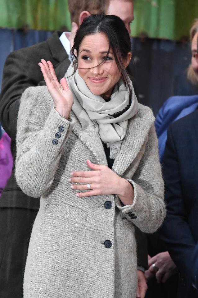 Meghan smiles cheekily as she arrives for the visit to Brixton