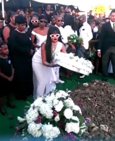 Rihanna is pictured laying flowers on her murdered cousin's grave at his funeral