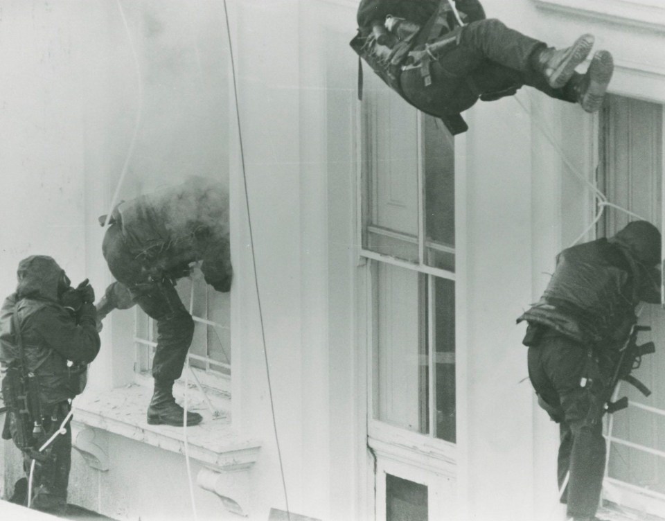 SAS fighters are pictured smashing through the windows of the Iranian embassy in London during their iconic raid in 1980