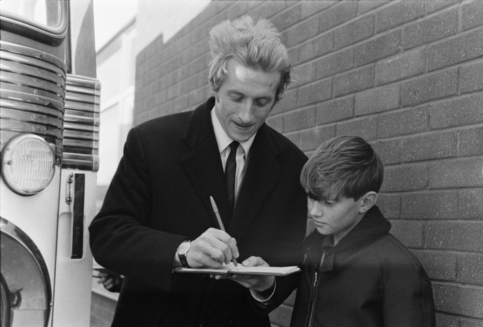 The Scot signs an autograph for a young fan after arriving at United in 1962