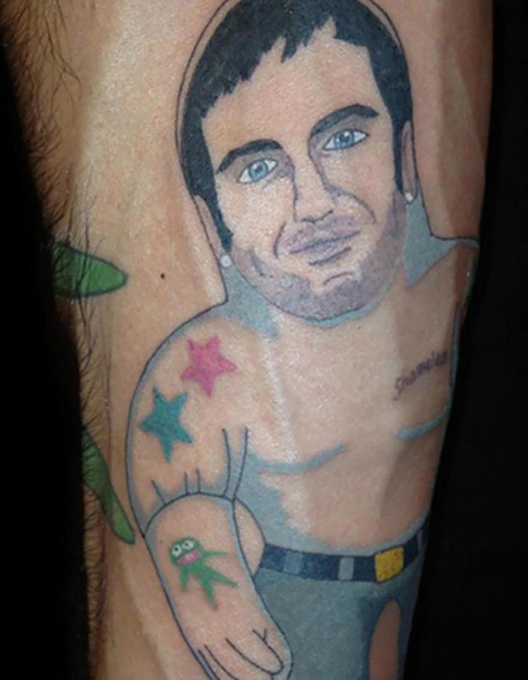 This arm tattoo displays what looks like a Don Draper sex doll wearing a Kermit the Frog oven glove