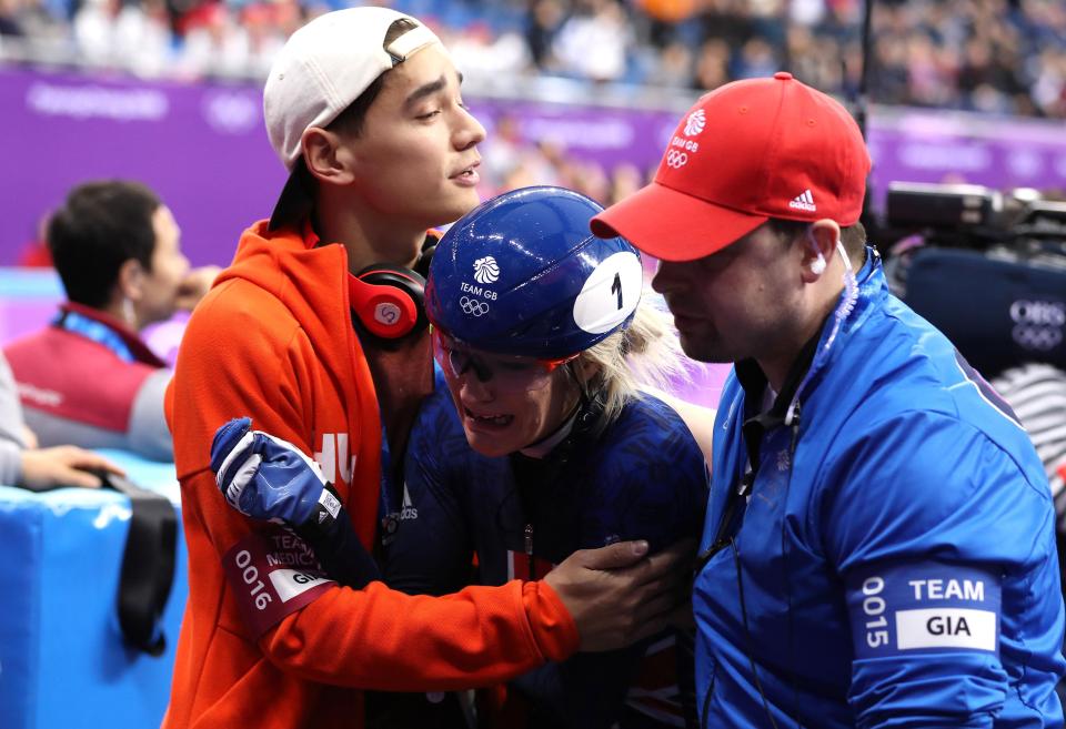  The speed skater gets consoled by her coaching team as she leaves the ice rink empty handed