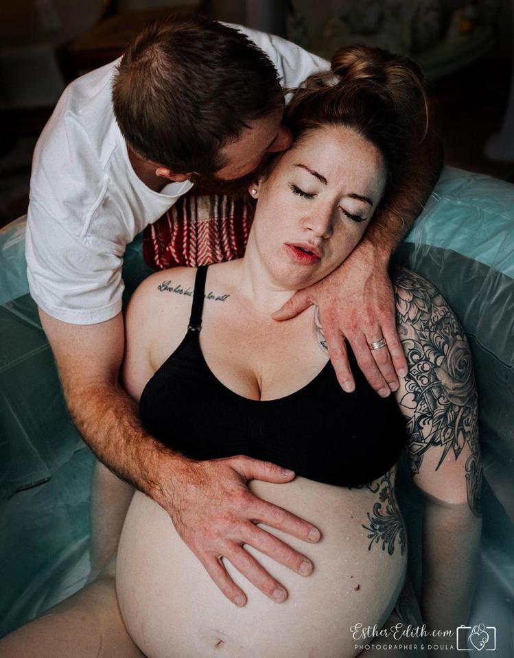 A woman is comforted by her partner as she gives birth in a pool 