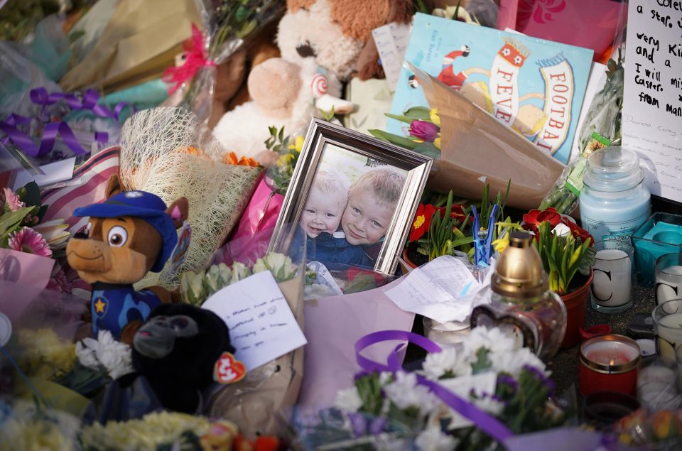  A photograph of the two boys sits among floral tributes and teddies at the scene