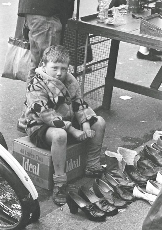  A young boy is seen sitting on a box with a number of shoes he just polished