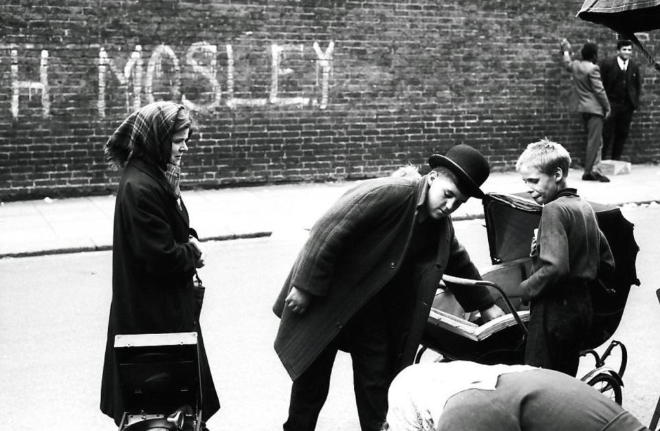  Graffiti is pictured on the wall behind a man tending to a baby in a push chair which says 'Mosley' - perhaps a nod to a Fascist MP who emigrated to Paris after his release from jail