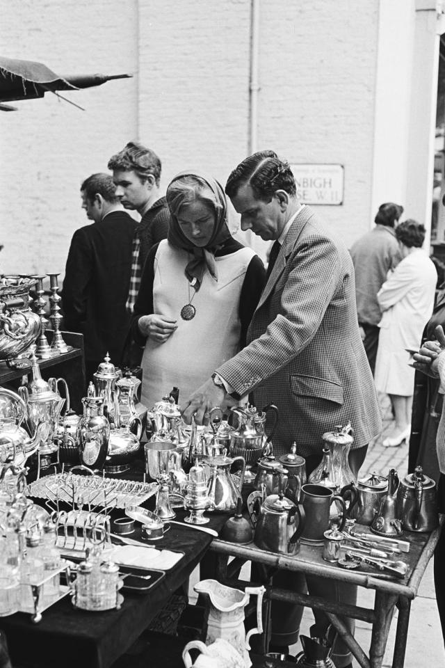  A man and woman are pictured looking at stall selling different types of tea pots